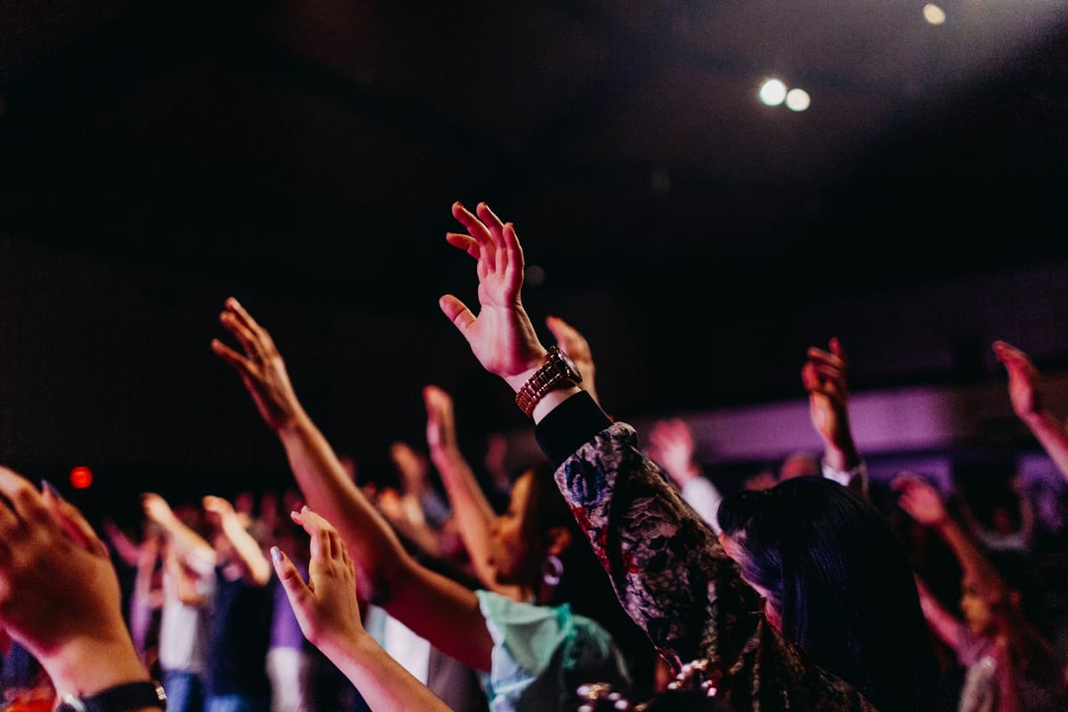 Hands raised in worship under stage lights